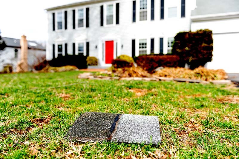 Asphalt Shingle debris from a roof on front lawn resulting from wind storm damage